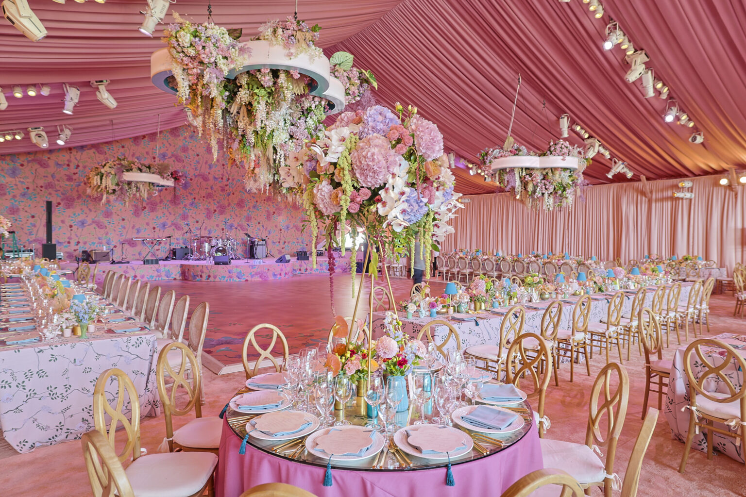 Extravagant wedding reception with draped pink tent ceilings and custom cascading floral chandelier. Designed by Rafanelli Events.
